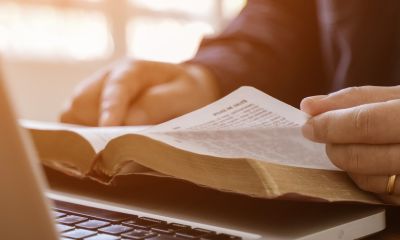 Laptop und aufgeschlagene Bibel