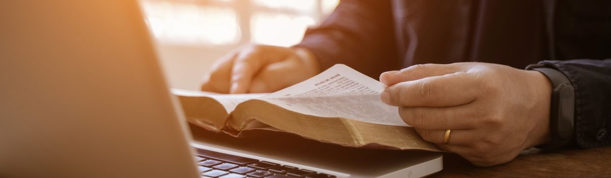 Laptop und aufgeschlagene Bibel