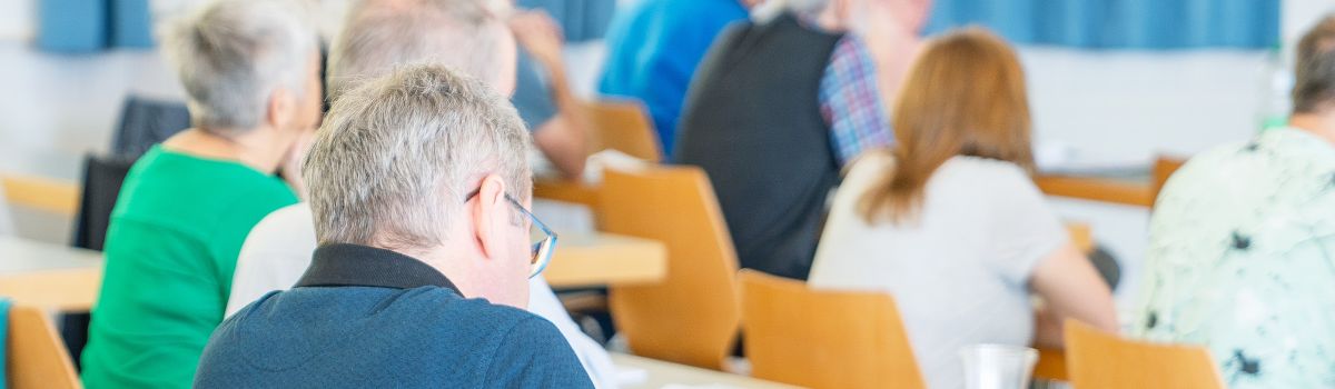 Teilnehmer in der Aula beim Zuhören
