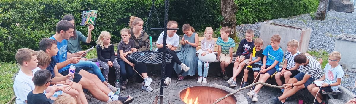Kindergruppe am Lagerfeuer hört eine biblische Geschichte